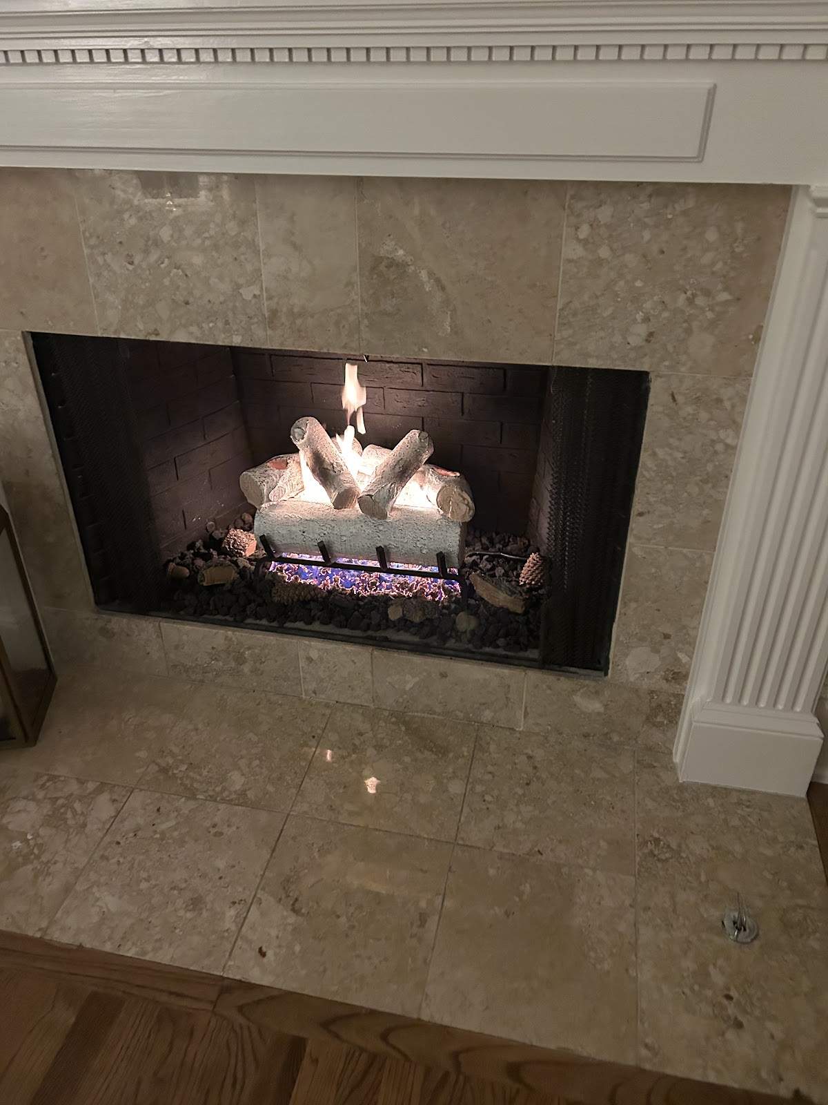 Lit gas fireplace with travertine marble surround